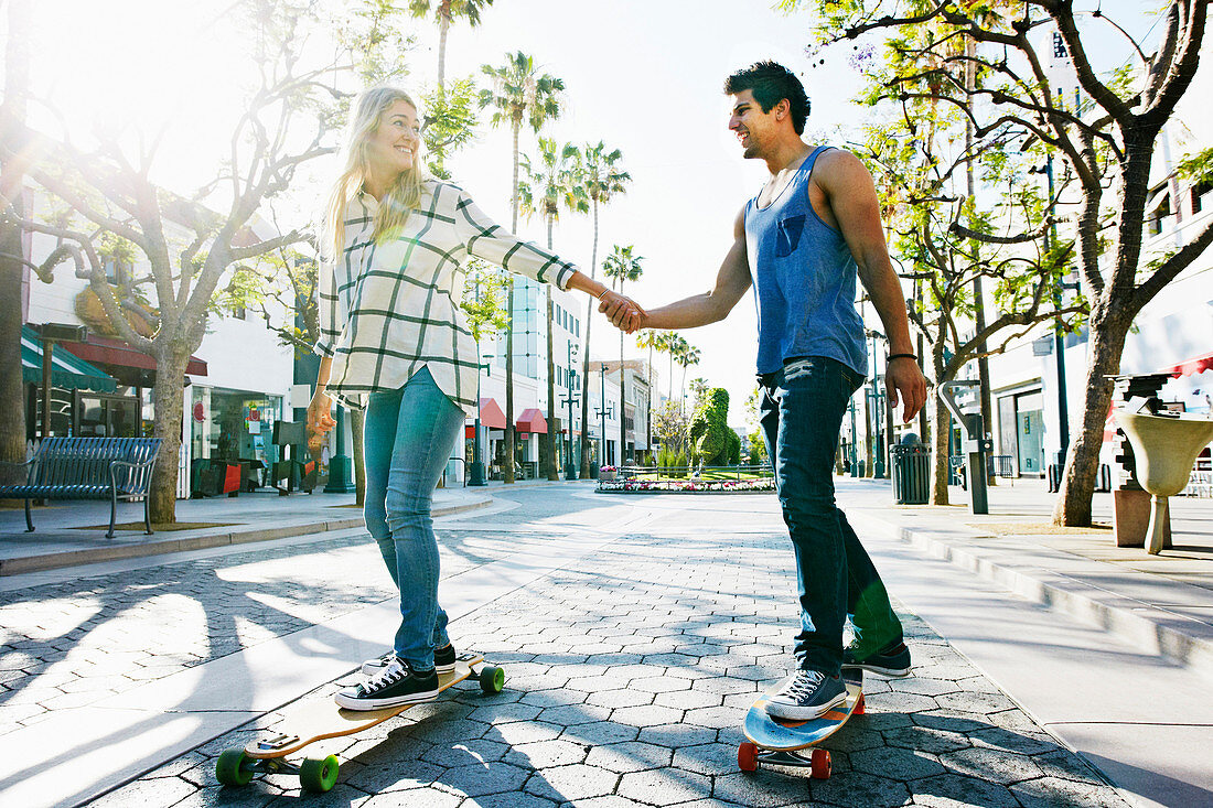 Kaukasisches Paar fährt Skateboard