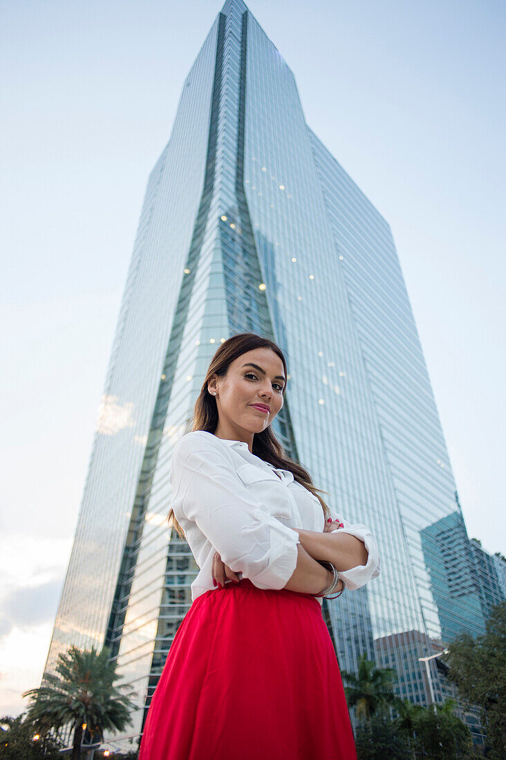 Hispanic businesswoman standing near highrise