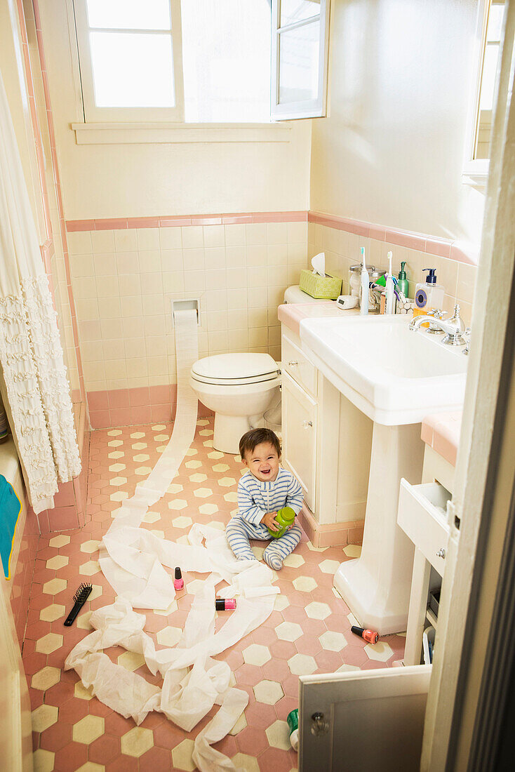 Baby boy playing in messy bathroom