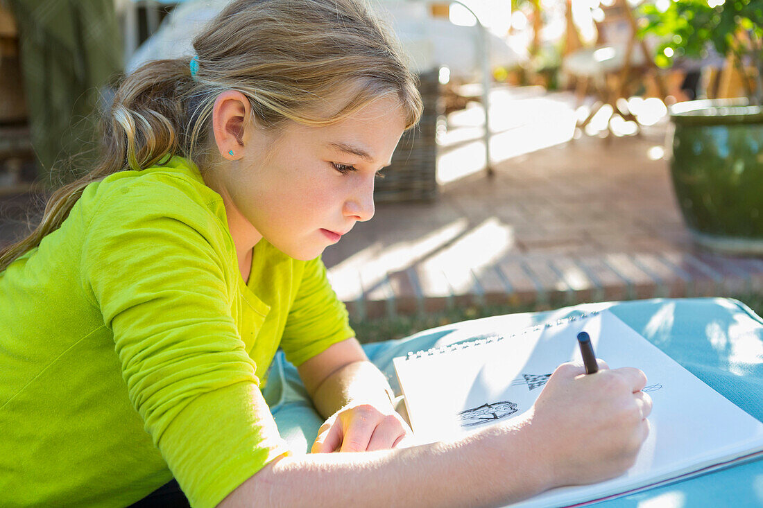 Caucasian girl drawing outdoors