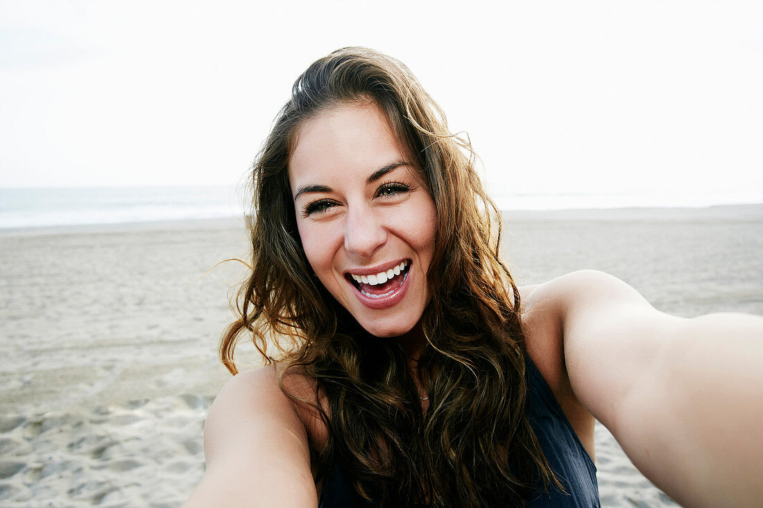 Mixed race woman taking selfie on beach