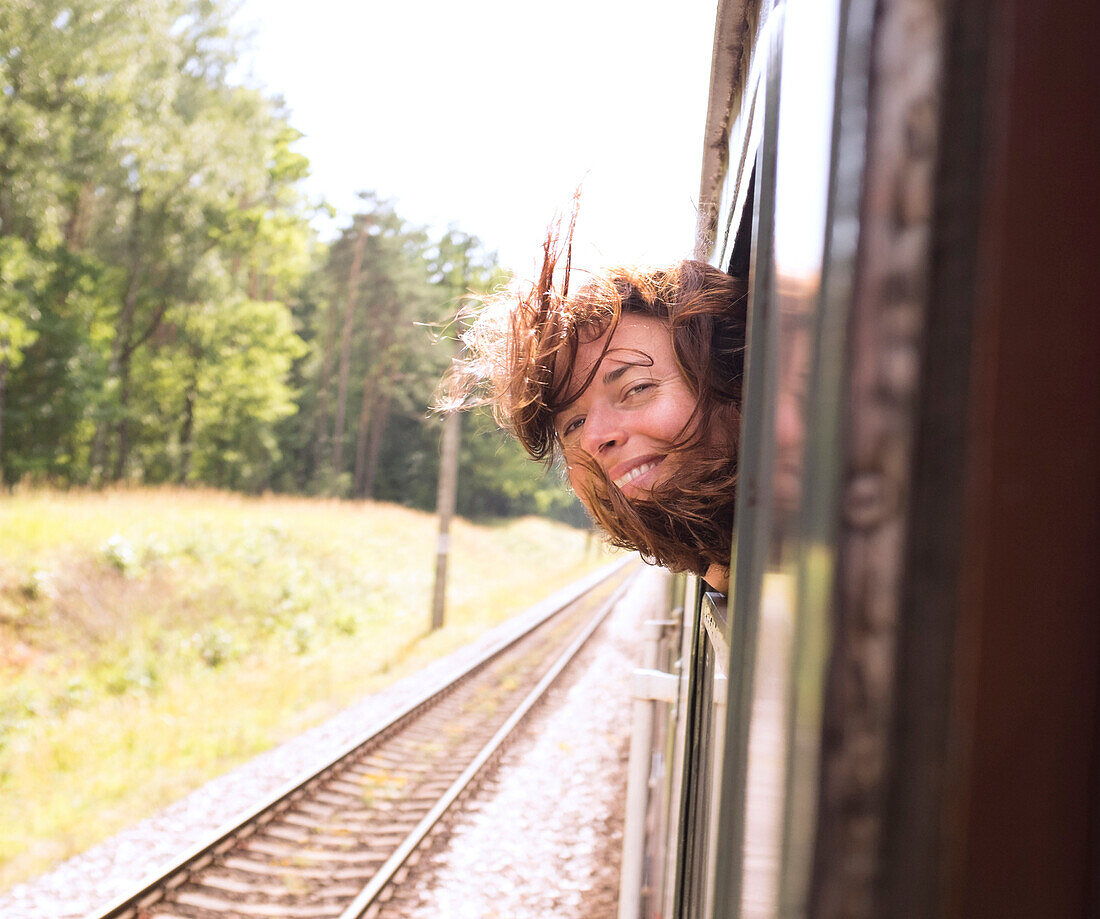 Hispanic woman with head out train window