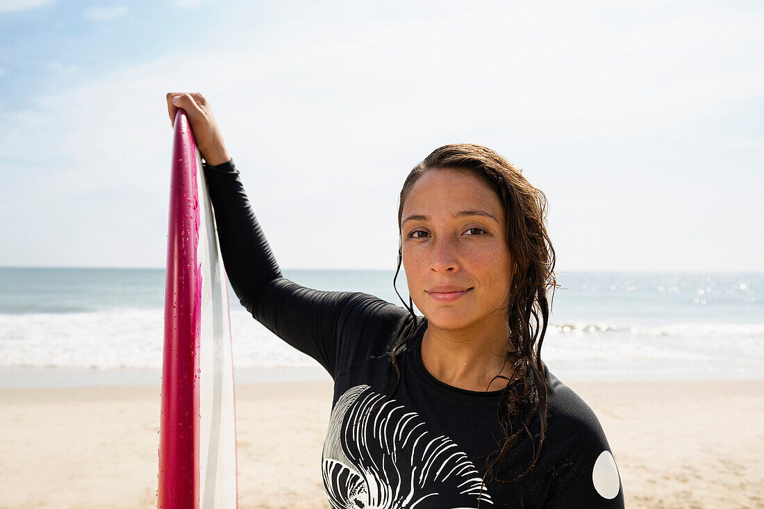 Hispanischer Surfer hält Surfbrett am Strand