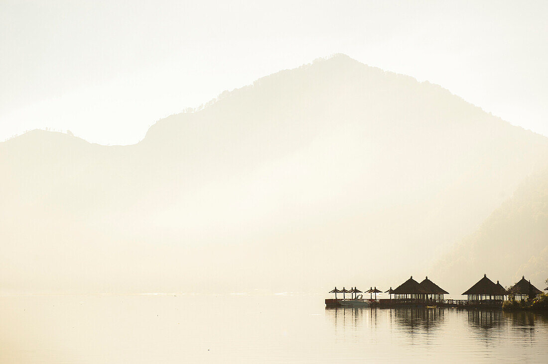 Huts reflecting in still remote lake under mountains