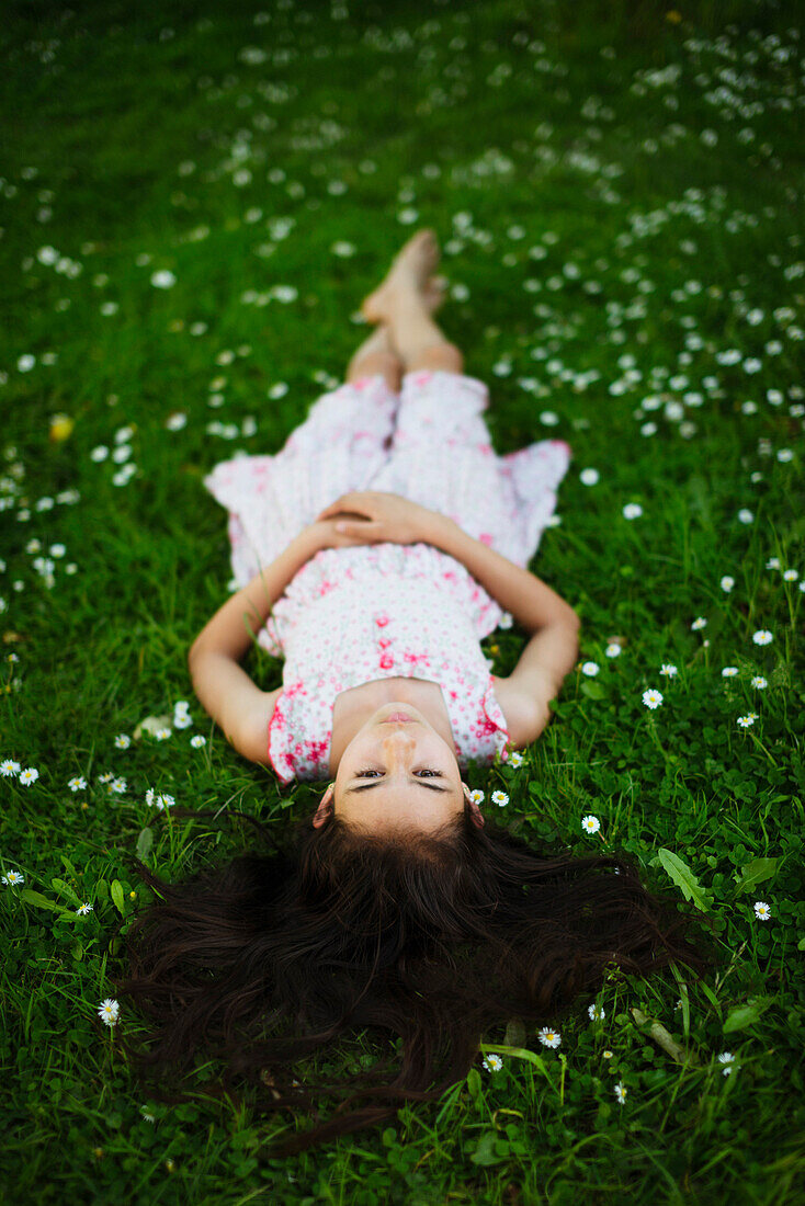 Mixed race girl laying in grass