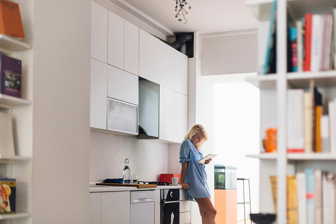 Woman using digital tablet in kitchen