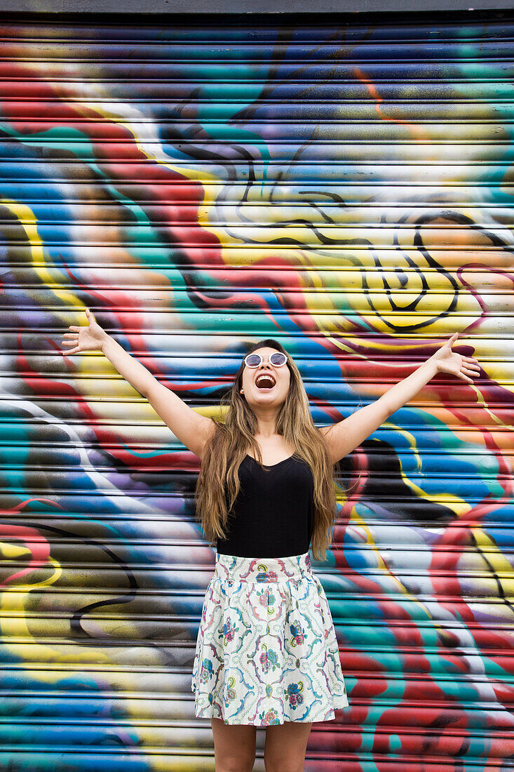 Asian woman cheering near graffiti wall