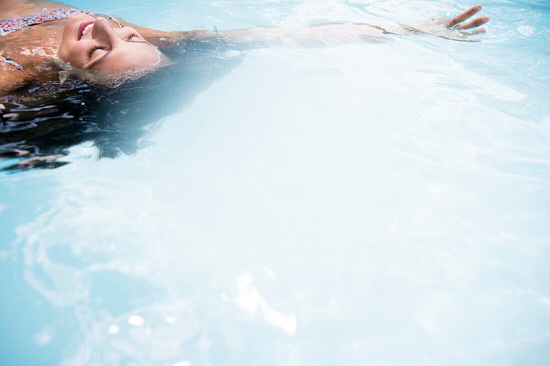 Caucasian woman floating in swimming pool