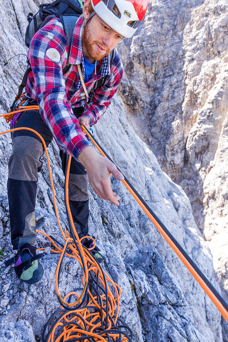 Climber pulling ropes up on the Herzogkante, Laliderer Northface, Lalidererspitze, Hinterriss, Ahornboden, Karwendel, Bavaria, Germany