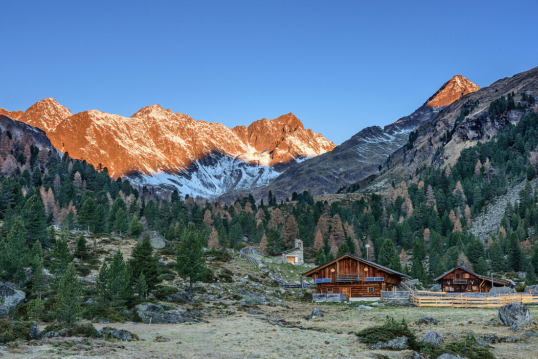 Alpine huts with Kleinschober, Debantgrat, Ralfkopf and Gloedis in alpenglow in background, valley of Debanttal, Schober Range, High Tauern, High Tauern National Park, East Tyrol, Tyrol, Austria