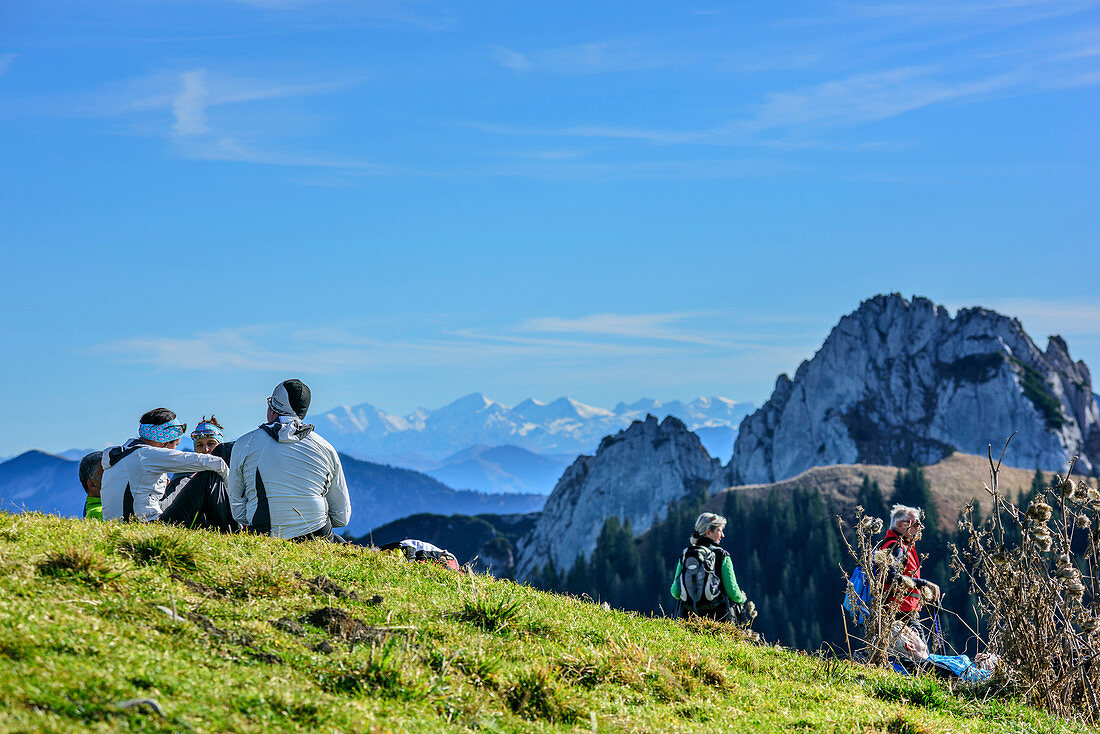 Several persons having a break at summit of Setzberg, High Tauern range and Plankenstein in background, Setzberg, Bavarian Alps, Upper Bavaria, Bavaria, Germany