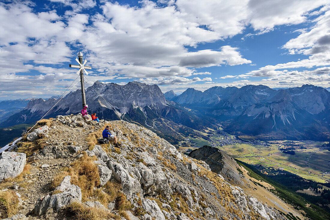 Mehrere Personen sitzen am Gipfel des Daniel, Zugspitze, Ehrwalder Becken und Mieminger Berge im Hintergrund, Daniel, Ammergauer Alpen, Tirol, Österreich