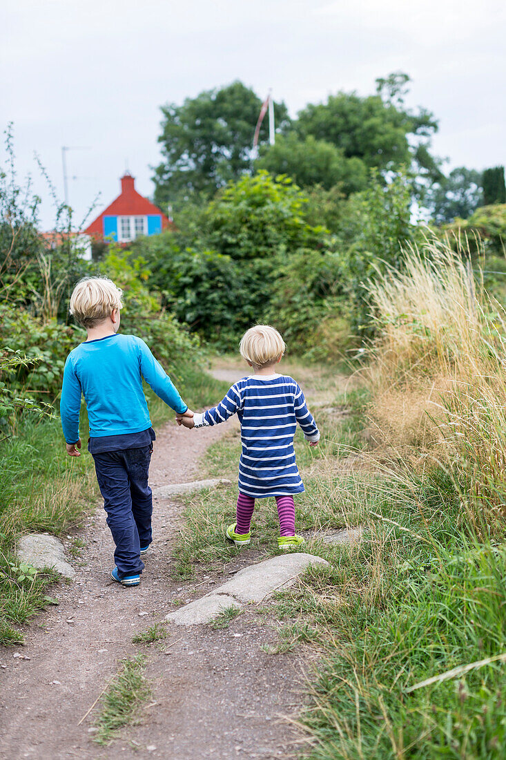 Siblings, children walking hand in hand, hiking trail from Svaneke to Listed, summer, Baltic sea, MR, Bornholm, Svaneke, Denmark, Europe