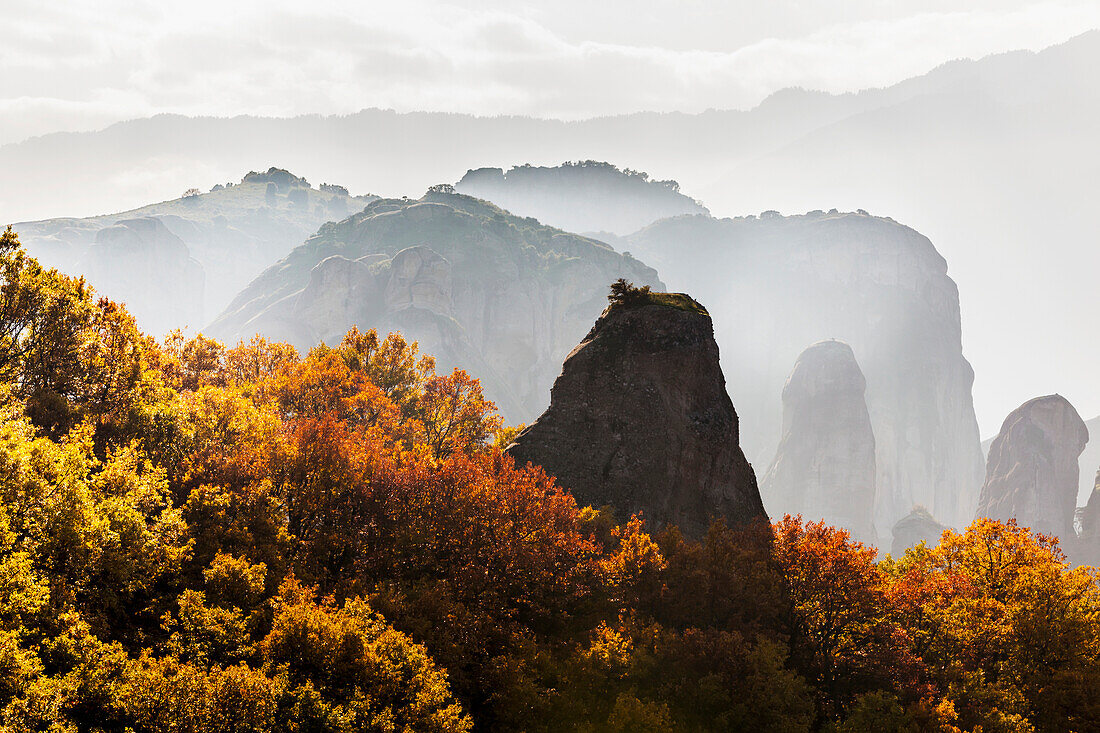 Low cloud around the rugged cliffs with foliage in autumn colours, Meteora, Greece