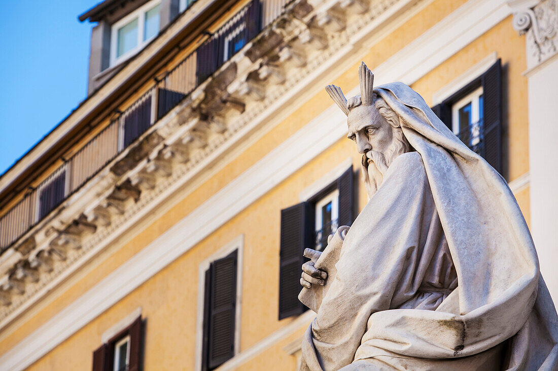 Statue of historical male figure and yellow building, Rome, Italy