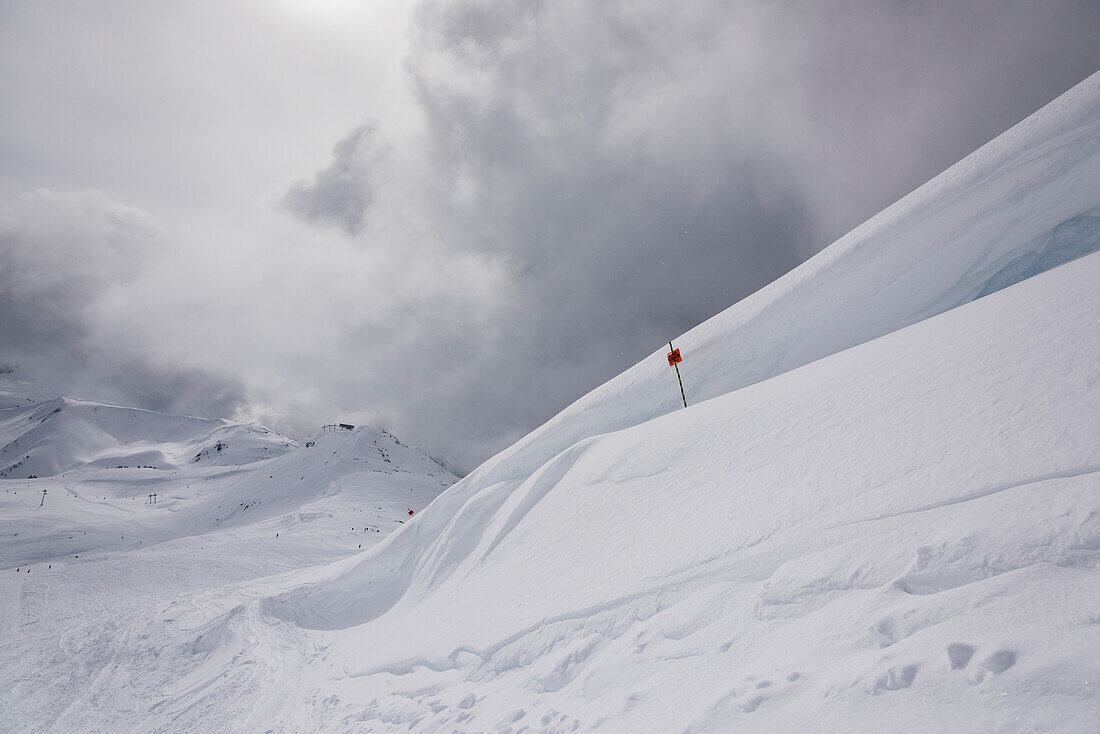 Drifting snow on a mountain top and a red flag on a ski run, Whistler, British Columbia, Canada
