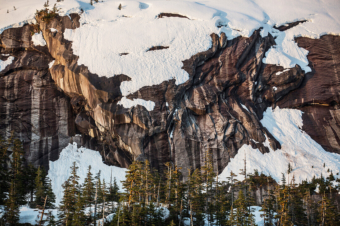 Scenic view of snow covered cliffs and evergreen trees at sunset, Kings Bay, Prince William Sound, Southcentral Alaska, USA, Winter
