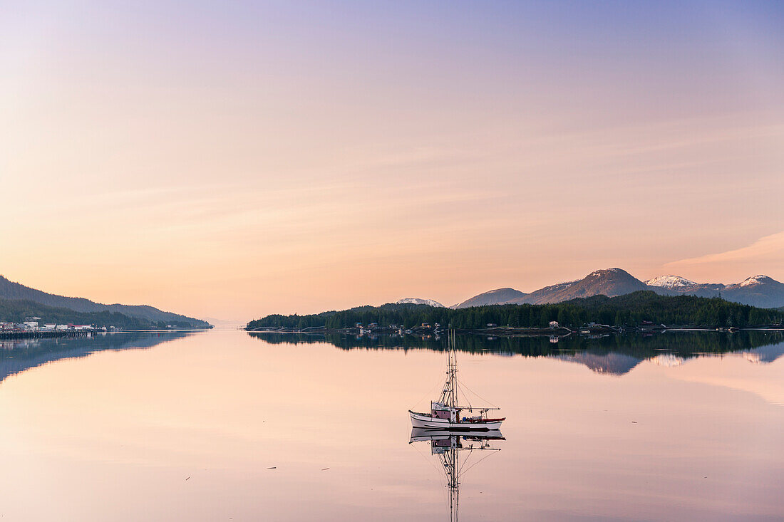 Scenic sunrise view of a small fishing boat reflecting in Ketchikan harbor, Southeast Alaska, Spring