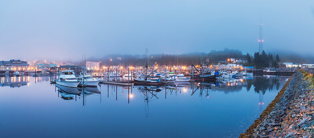 Panorama of boats in Ketchikan Harbor reflecting on the calm ocean waters on a foggy night, Ketchikan, Southeast Alaska