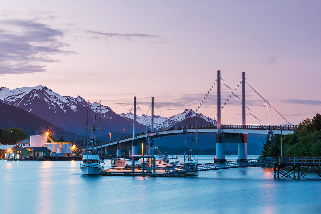 Fishing boat moored along the pier in Sitka Harbor with O'Connell Bridge and the mountains in the background at twilight, Southeast Alaska, USA, Summer