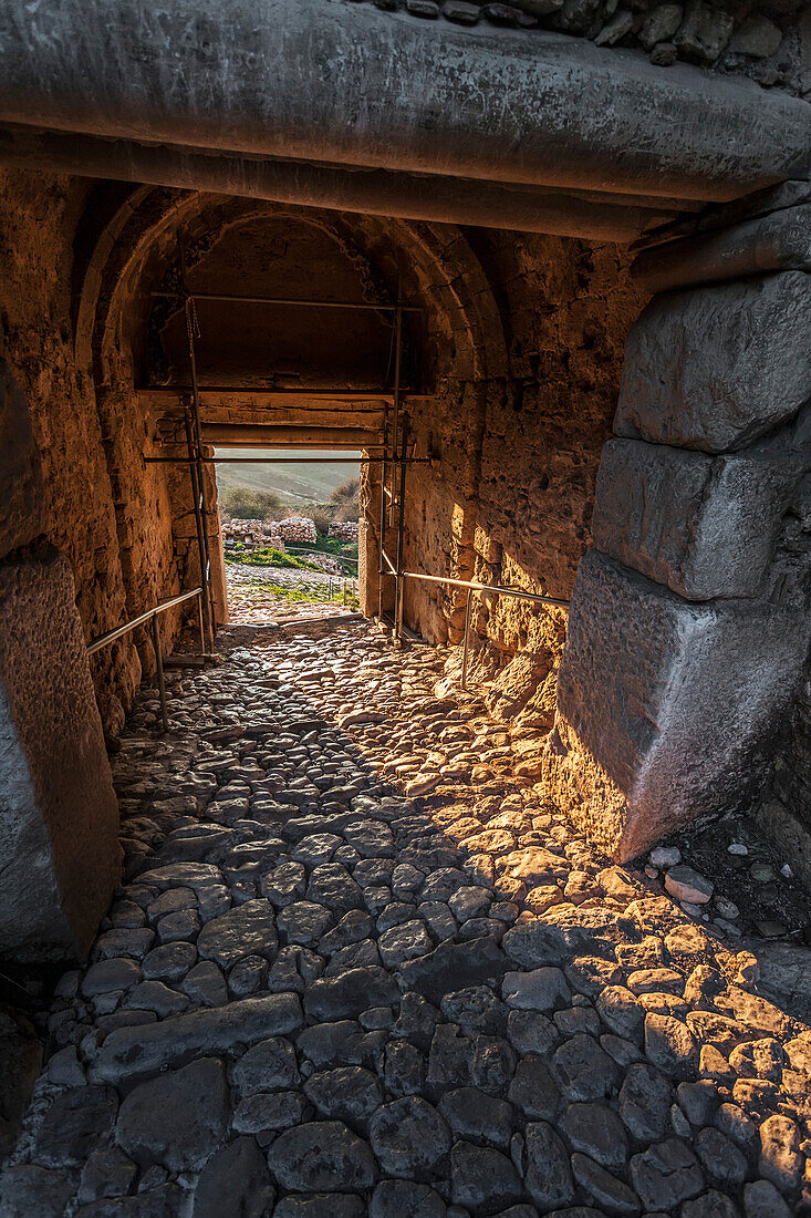 Interior of a building with arched roof, stone beams and cobblestone ground, Corinth, Greece