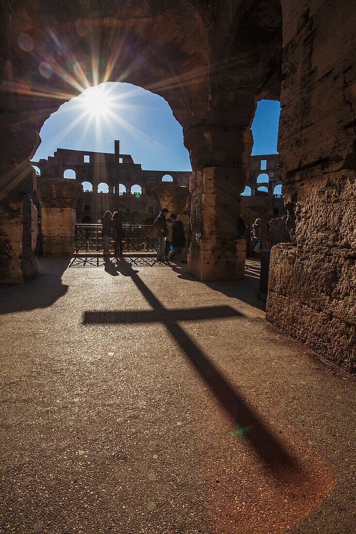 Sunburst through an archway at the Colosseum and a shadow of a cross, Rome, Italy