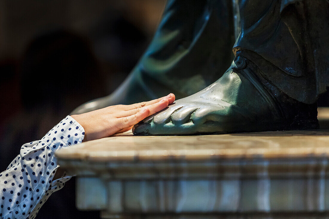 A woman's hand touches the foot of a statue, St. Peter's Basilica, Rome, Italy
