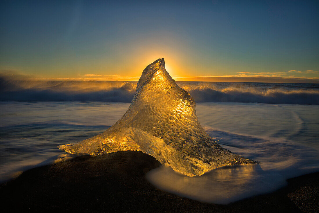 A peaked ice formation glowing golden in the sunlight, Iceland