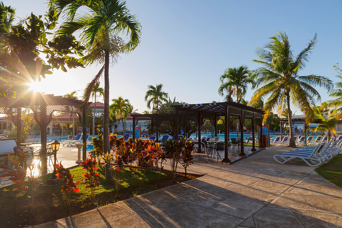 The sun setting through the palm trees and creates long shadows on the pool deck at this resort in Cuba, Varadero, Cuba
