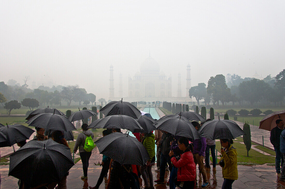 eine Gruppe Menschen mit schwarzen Regenschirmen vor dem Taj Mahal, Agra, Uttar Pradesh, Indien