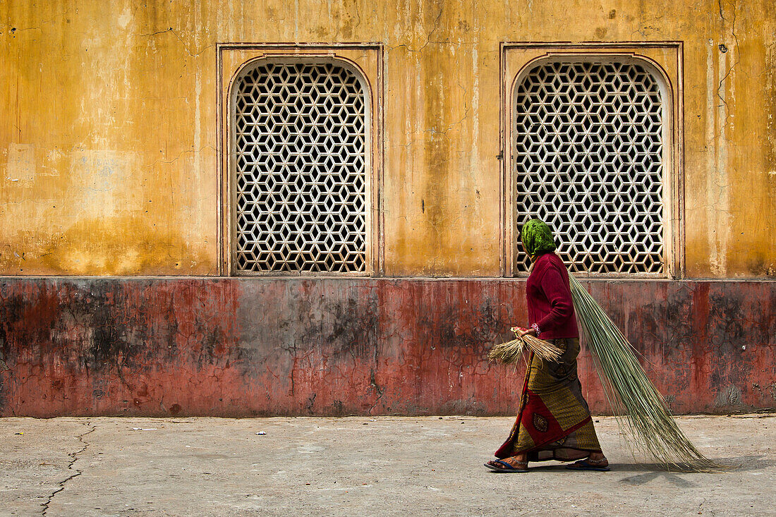 Frau mit Bambusbesen vor einem Gebäude der Galtaji Tempelanlage, Jaipur, Rajasthan, Indien