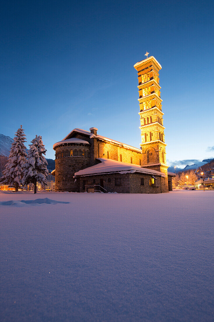 Dusk and lights on the church surrounded by snow Sankt Moritz, Engadine, Canton of Grisons Graubunden, Switzerland, Europe