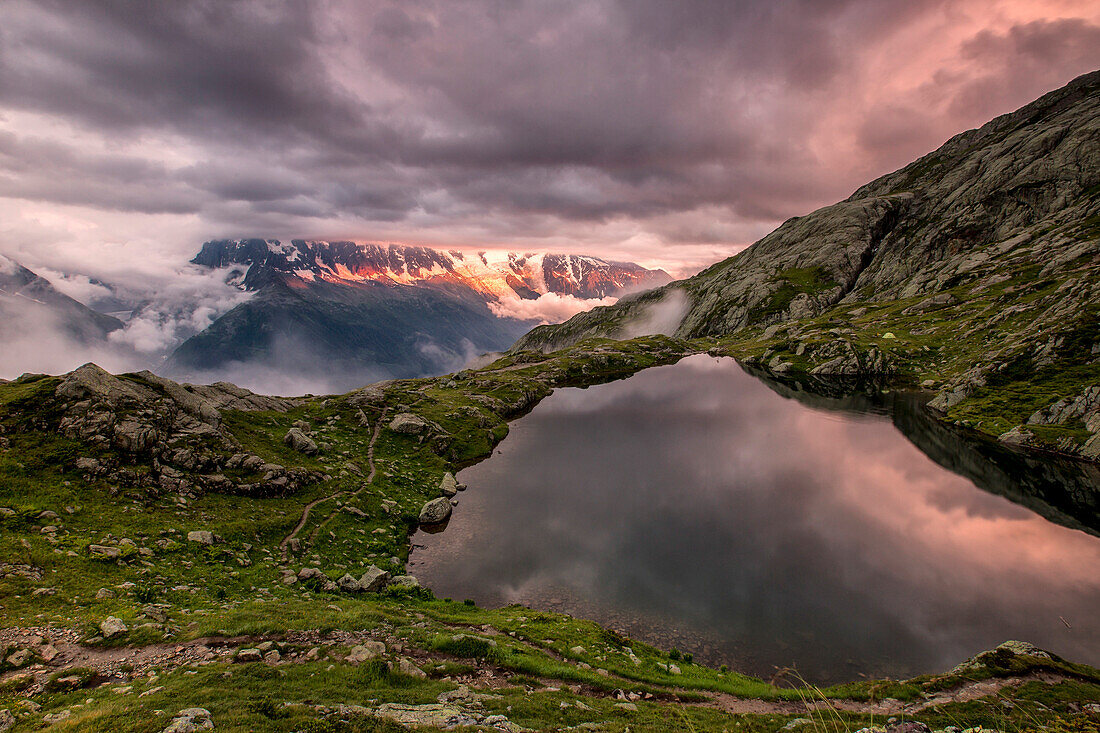 Clouds are tinged with purple at sunset at Lac de Cheserys, Chamonix, Haute Savoie, French Alps, France, Europe