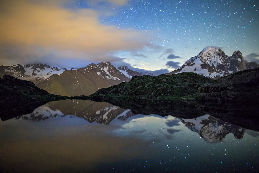The stars illuminate the snowy peaks and reflected in Lac de Cheserys, Chamonix, Haute Savoie, French Alps, France, Europe