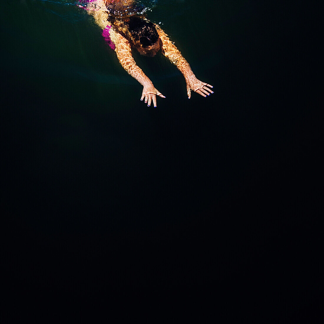 Elevated view of a woman emerging from underwater in the Russian River in Monte Rio, California.