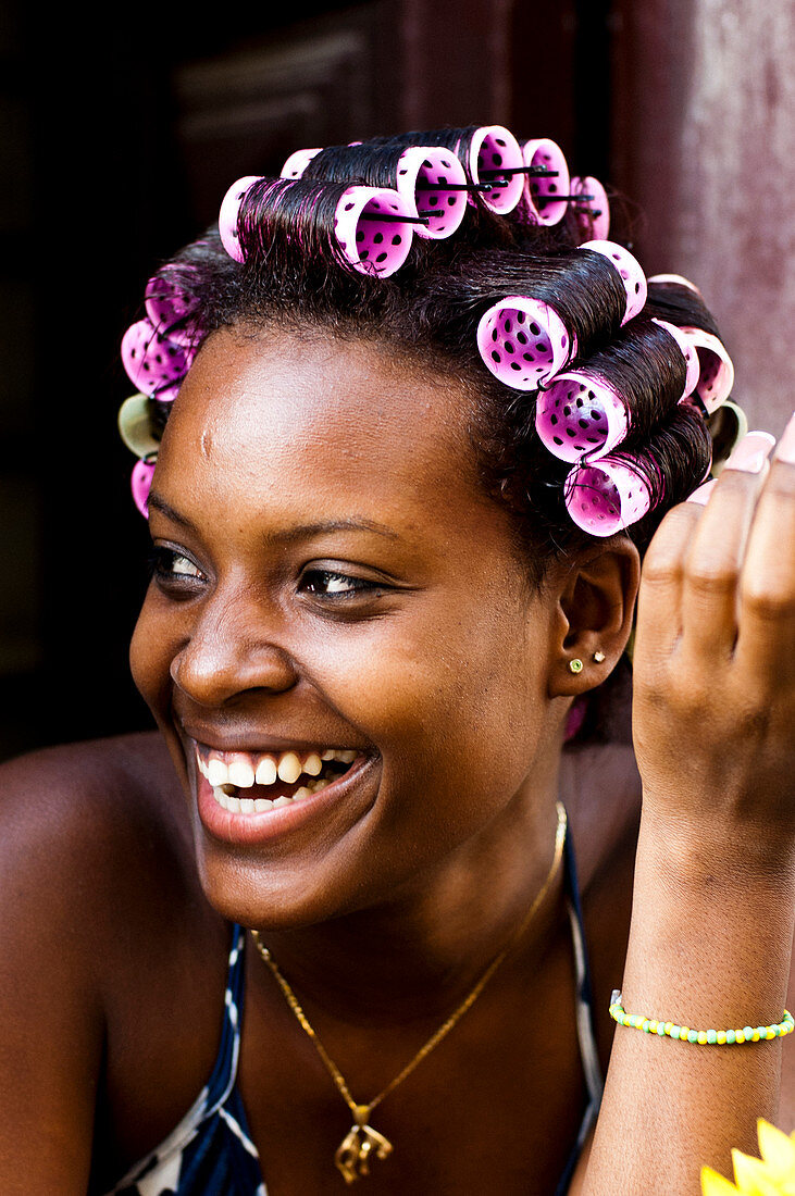 A local Cuban girl smiles with curlers in her hair in Havana, Cuba.