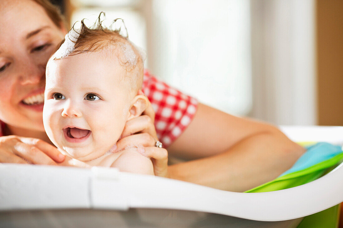 Caucasian mother bathing baby daughter