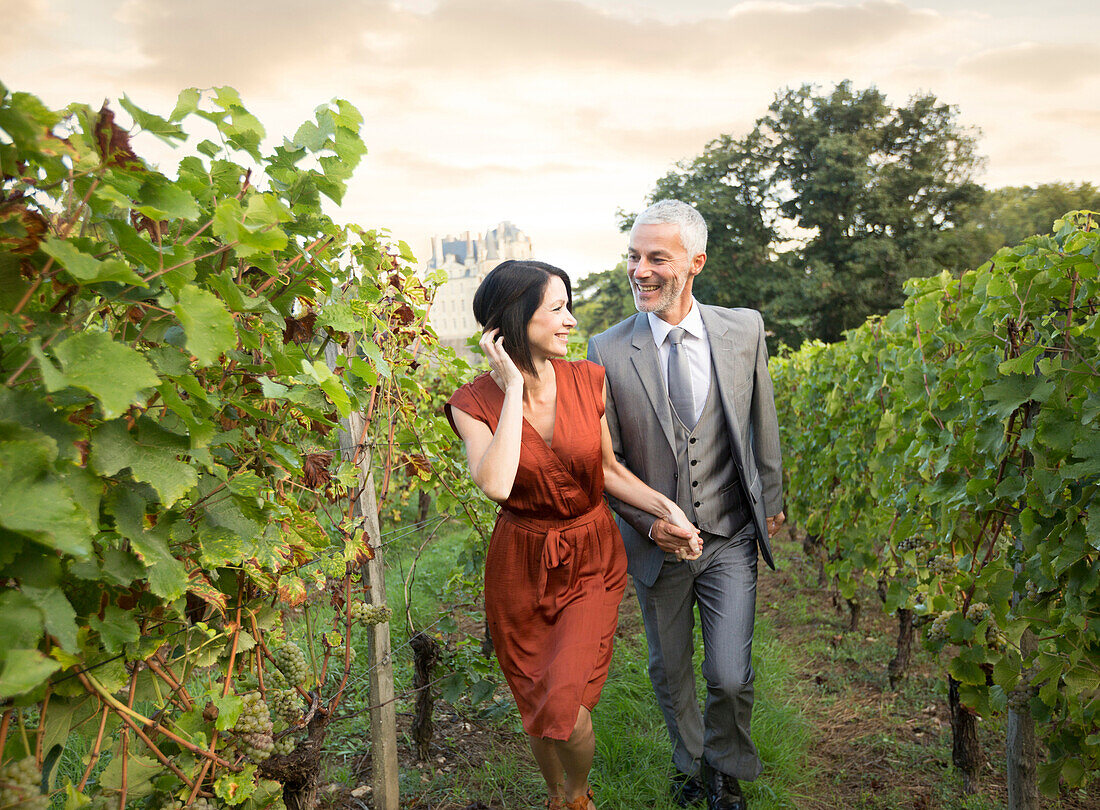 Caucasian couple walking in vineyard