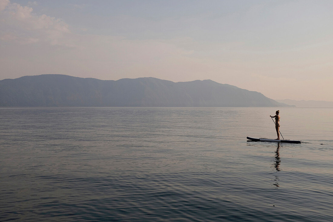 Caucasian woman standing on paddleboard in lake