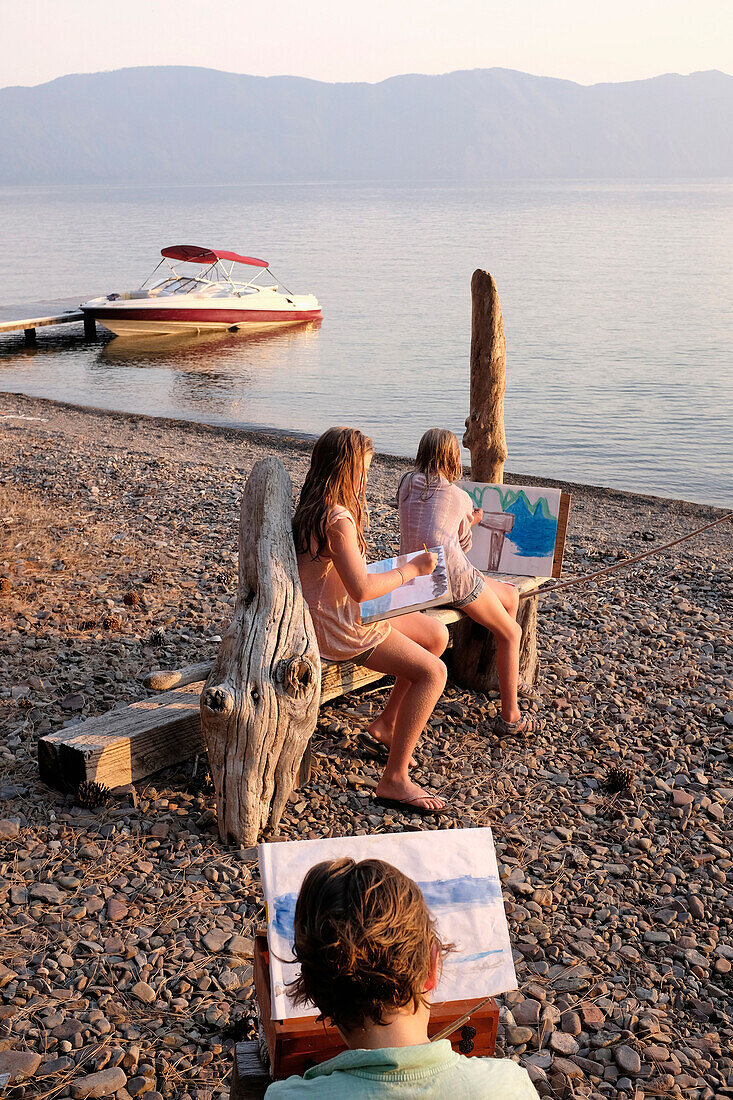 Caucasian family painting on remote lake