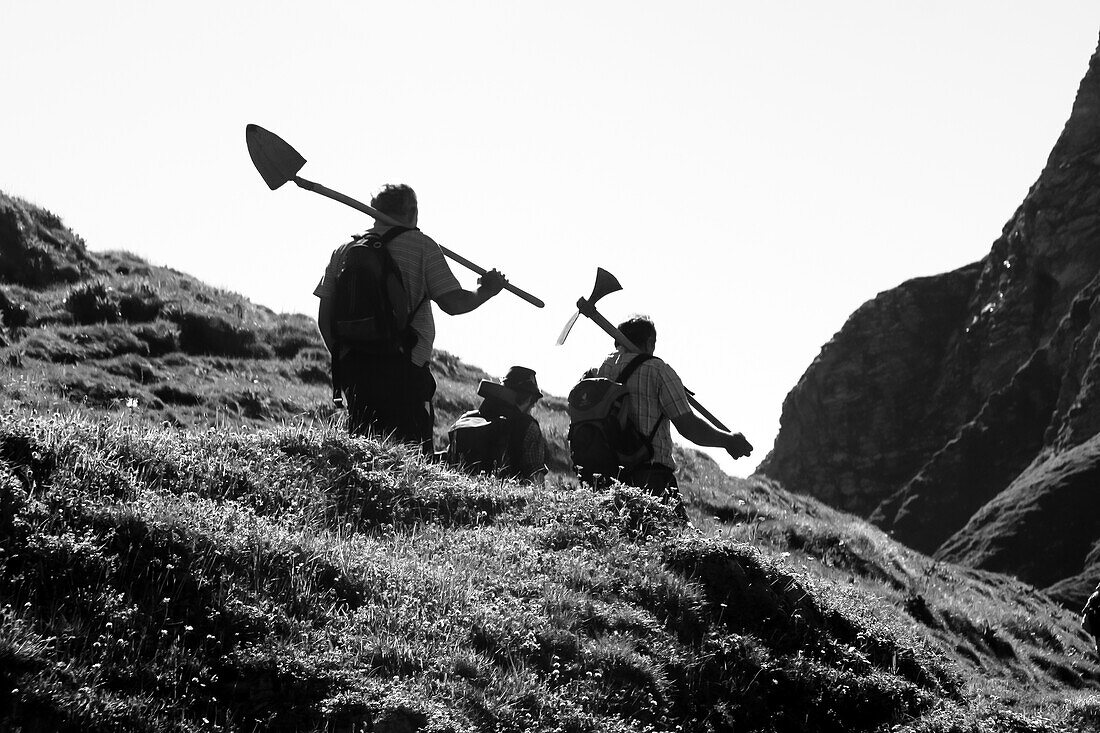 Schwarz/Weiß Aufnahme von Arbeitern mit Werkzeugen in den Händen beim Wandern in den Bergen, Oberstdorf, Deutschland