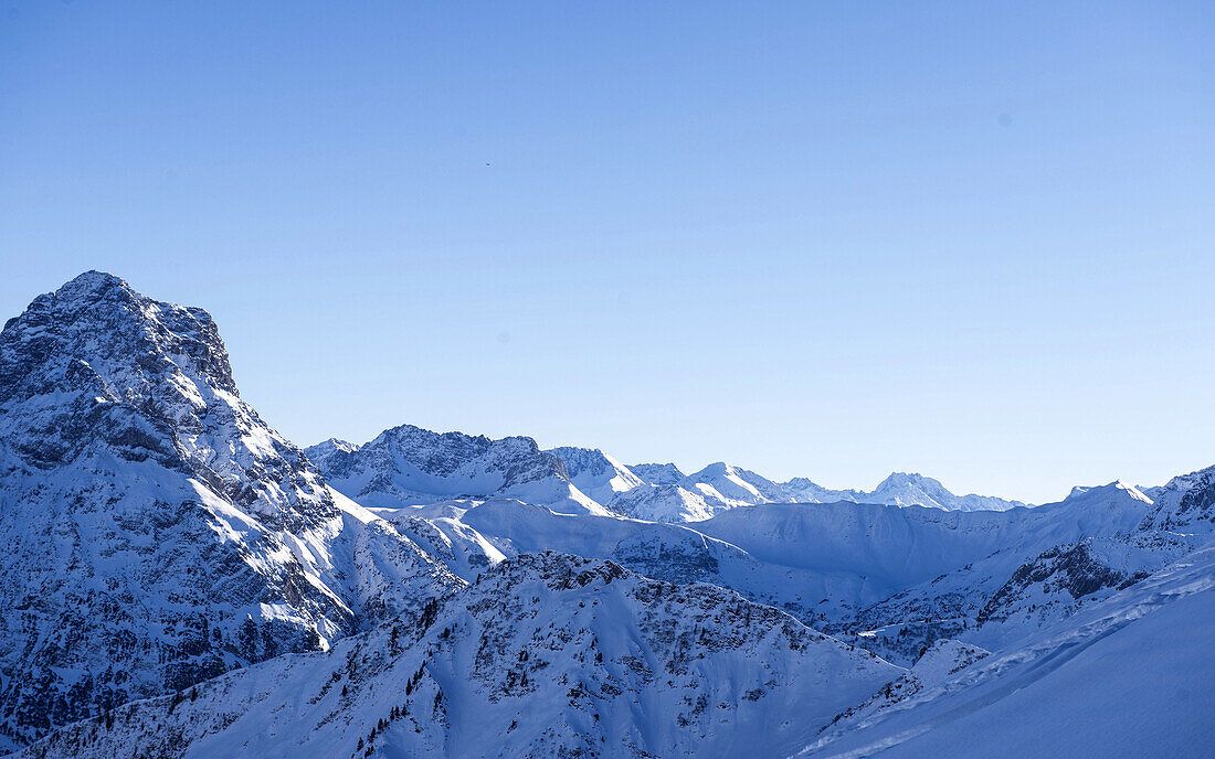 Blick auf die verschneiten Bergspitzen bei blauem Himmel und Sonnenschein rund um den Berg Ifen, Vorarlberg, Österreich