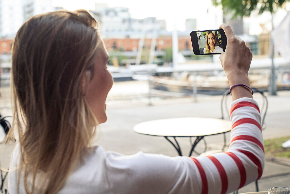 Young woman posing for a selfie at outdoor cafe