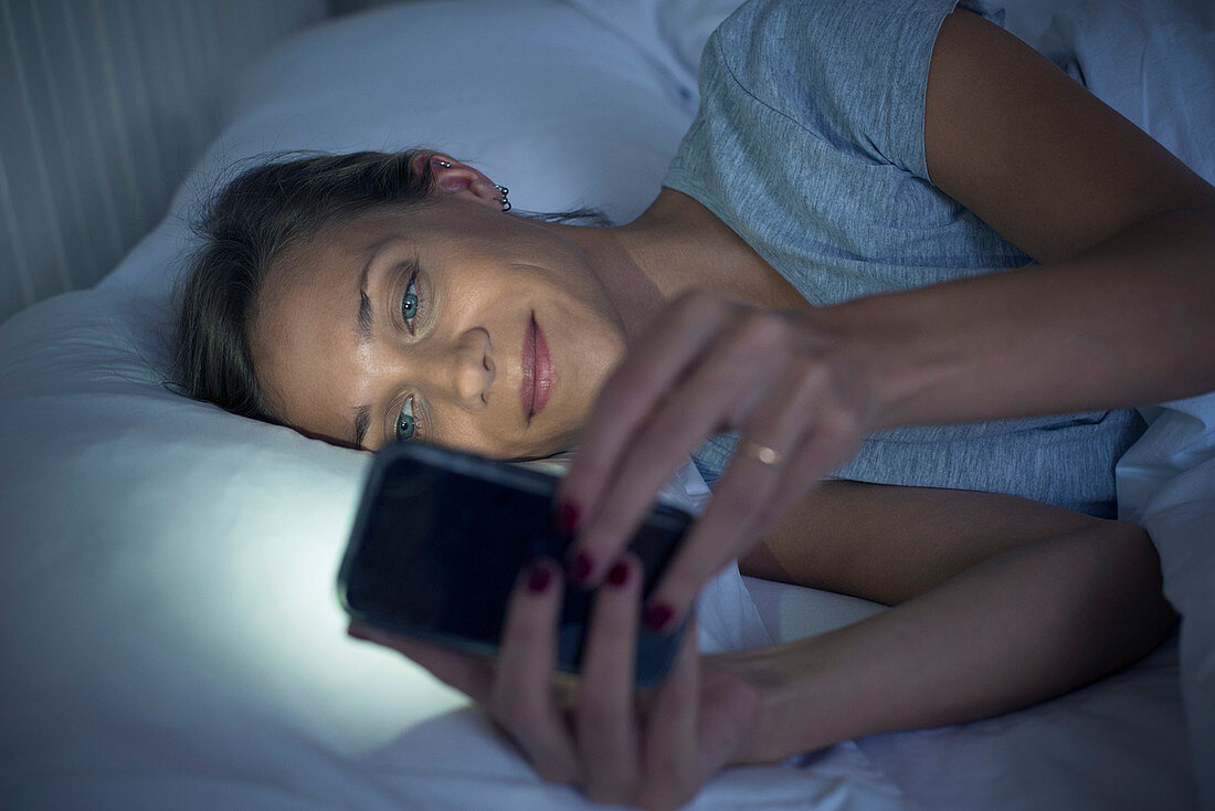 Woman in bed using smartphone
