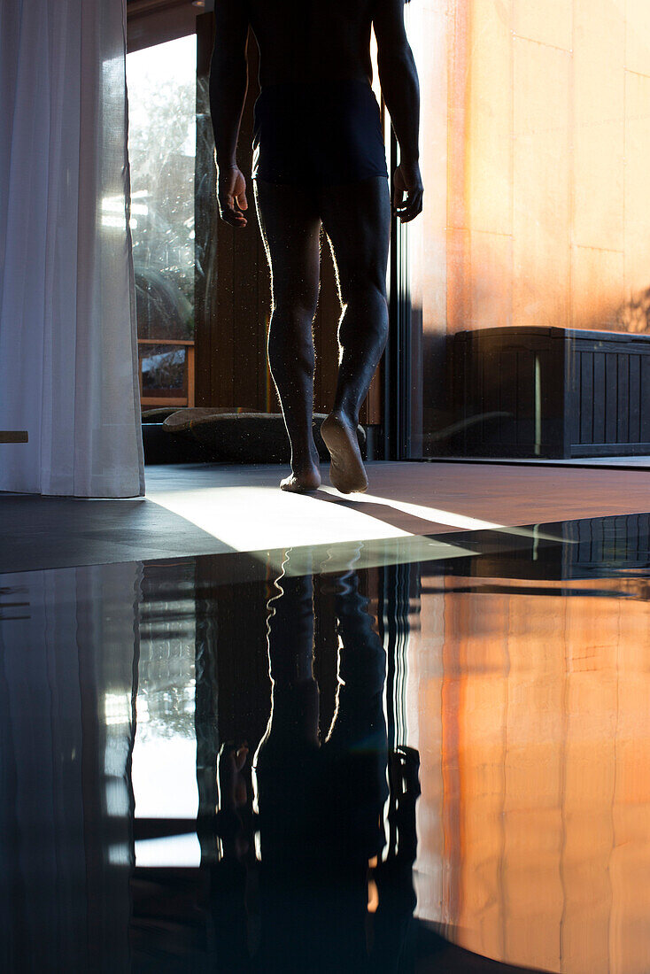 Man walking away from indoor pool, cropped