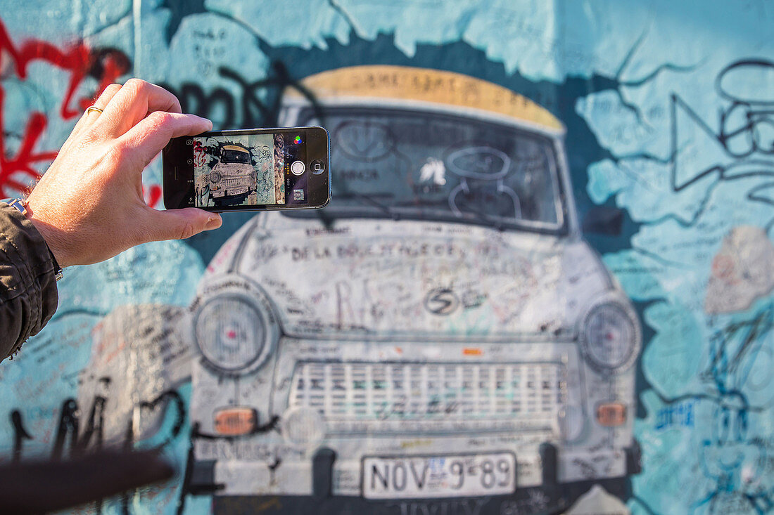 a trabant in a mural on a preserved part of the berlin wall at the east side gallery, berlin, germany