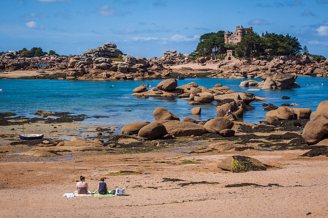 bathers soaking up the sun on a beach in ploumanac'h while enjoying the view of the chateau de costaeres and the pink granite coast, ploumanac'h, (22) cotes d'armor, brittany, france