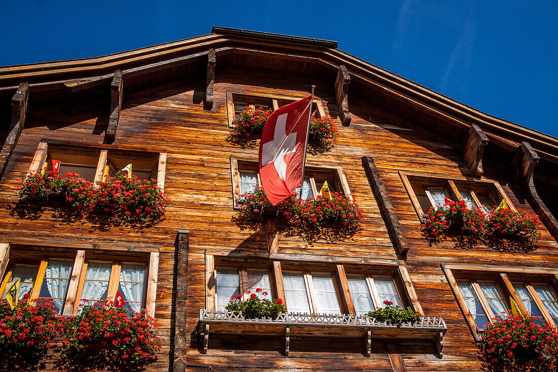 drapeau suisse flottant au balcon d'un chalet traditionnel dans le village d'andermatt, andermatt, canton d'uri, suisse
