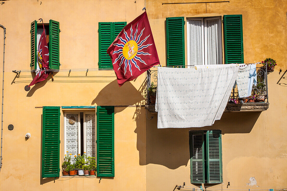 drapeau d'une confrerie du palio ornant le balcon d'un immeuble d'un quartier de sienne, sienne, italie, union europeenne