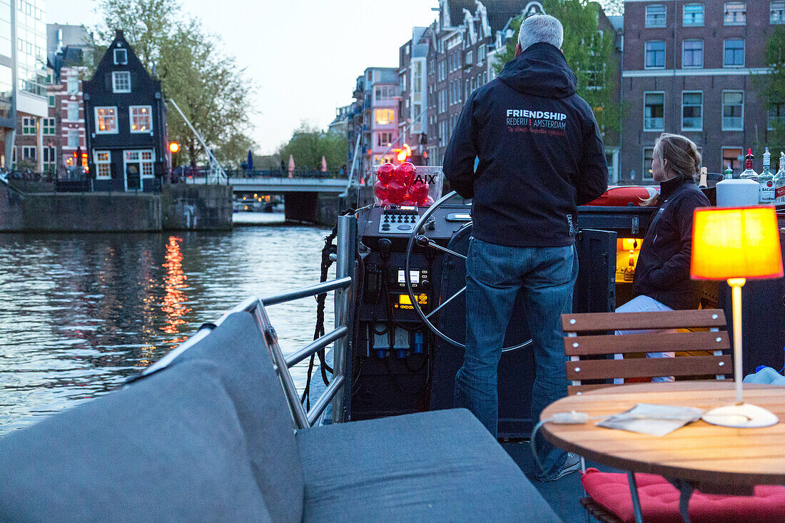 boat ride on the canals in front of the sluyswacht cafe from 1695, zwanenburgwal canal, amsterdam, holland